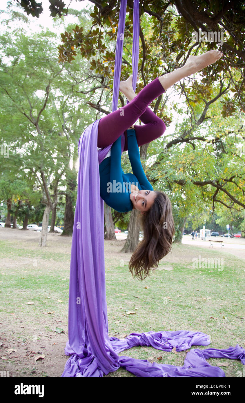 Giovane donna facendo acrobazie nella struttura ad albero Foto Stock