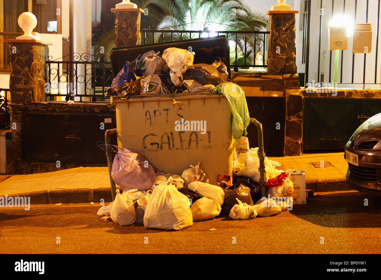 Traboccante communial contenitore di rifiuti al di fuori appartamenti vacanze in Spagna Foto Stock