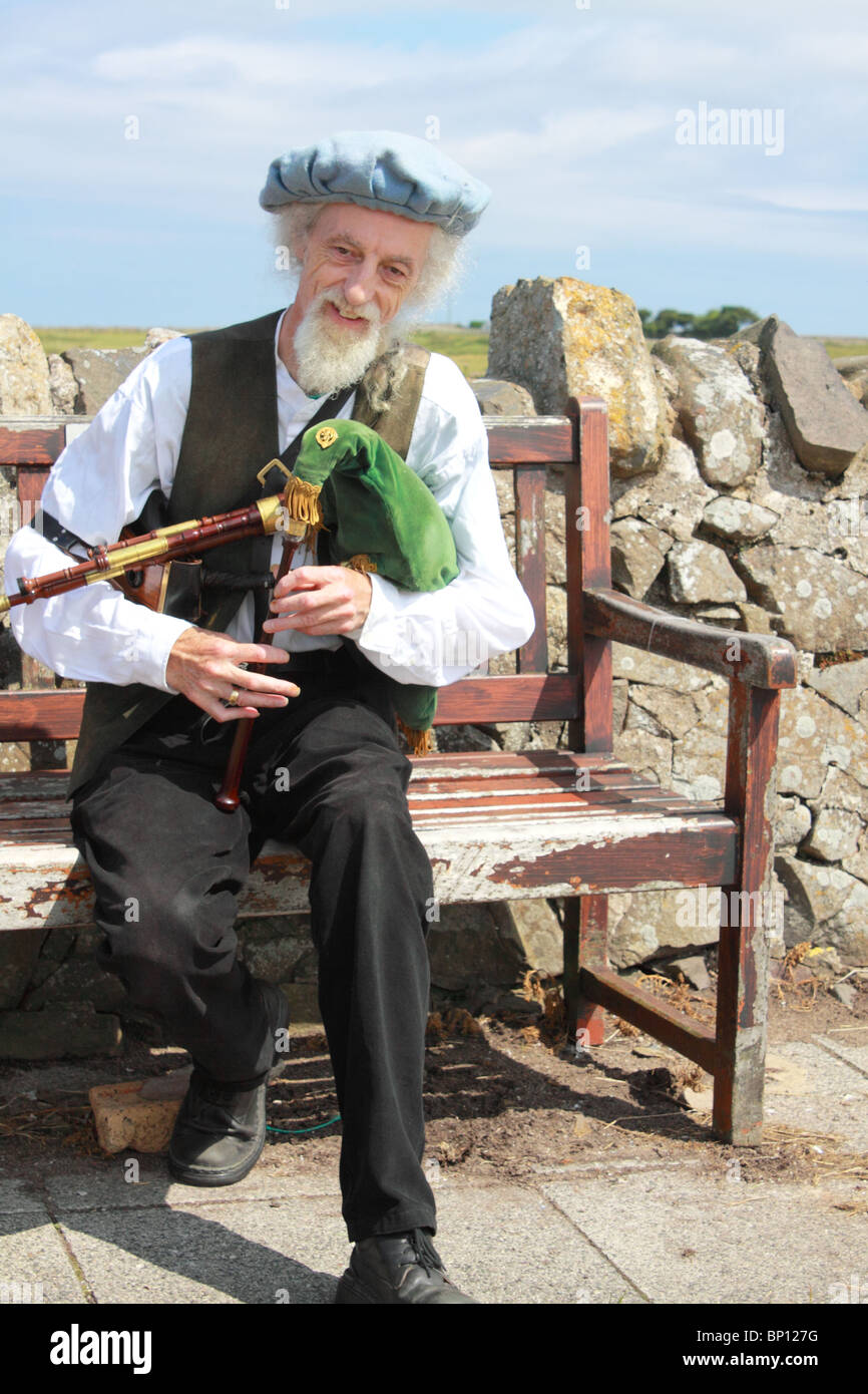 Musicista locale giocando Northumbrian piccoli tubi a Lindisfarne / Isola Santa, Northumberland, England, Regno Unito Foto Stock