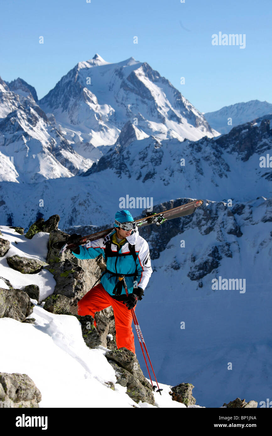 Francia, Alpi, Savoie, Courchevel, sciatore tenendo gli sci, La Grande casse in background Foto Stock