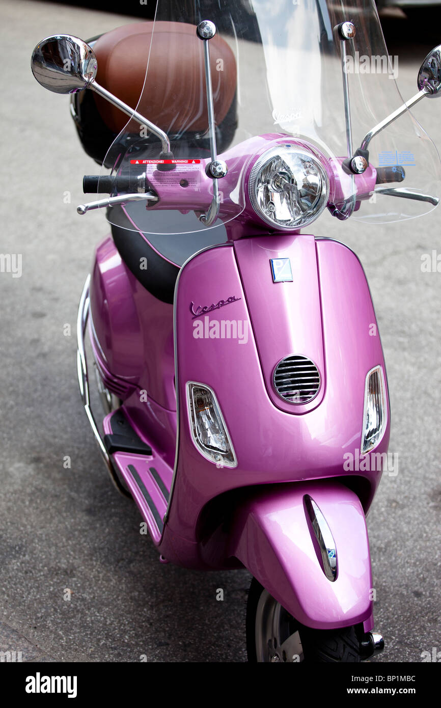 Pink scooter Vespa parcheggiata su una strada Foto Stock