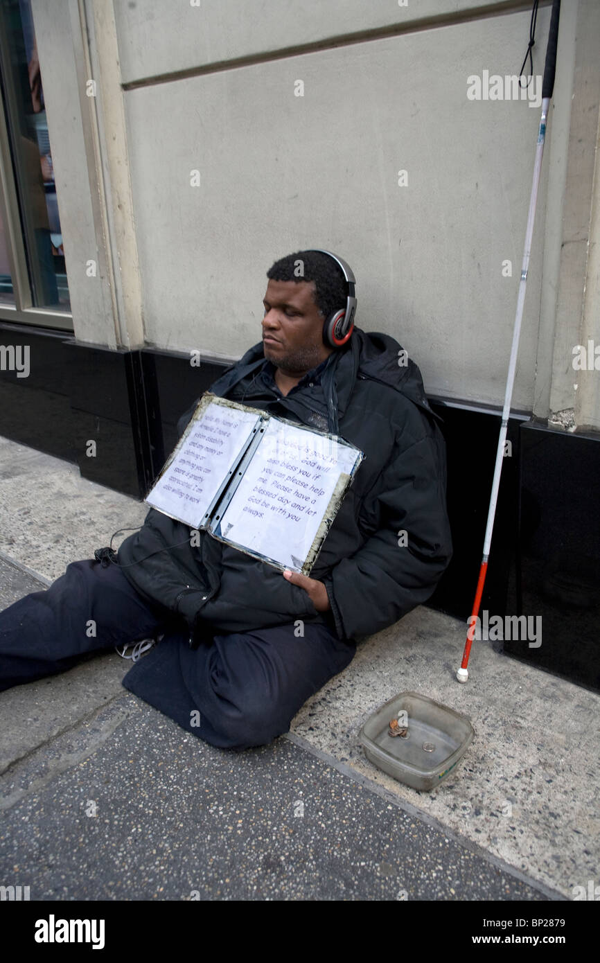 Cieco con auricolari, panhandling per denaro in midtown Manhattan, a New York City. Foto Stock