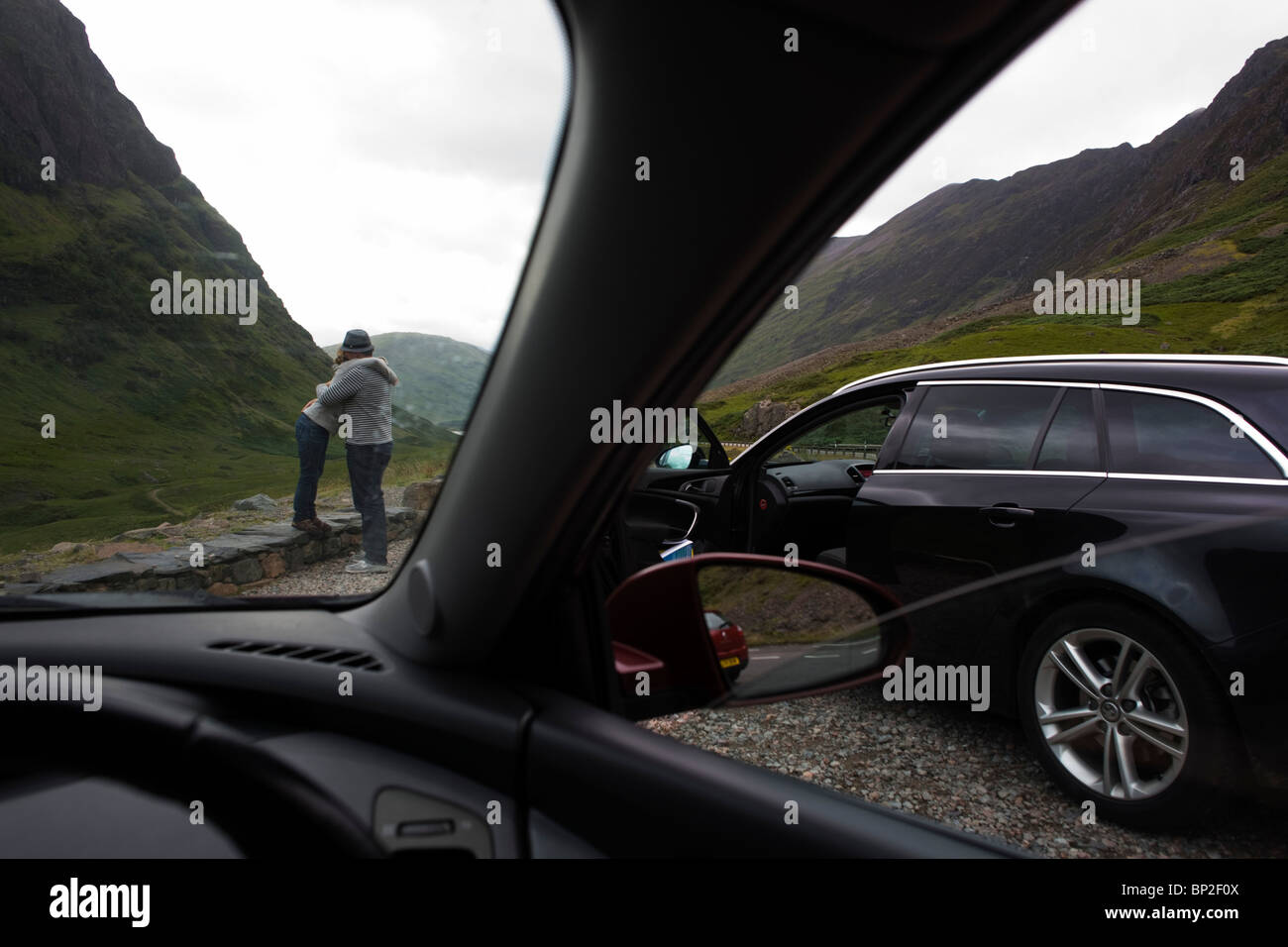 Coppia abbraccio spontanea durante la vettura ferma viaggio attraverso Glencoe, Scozia. Foto Stock