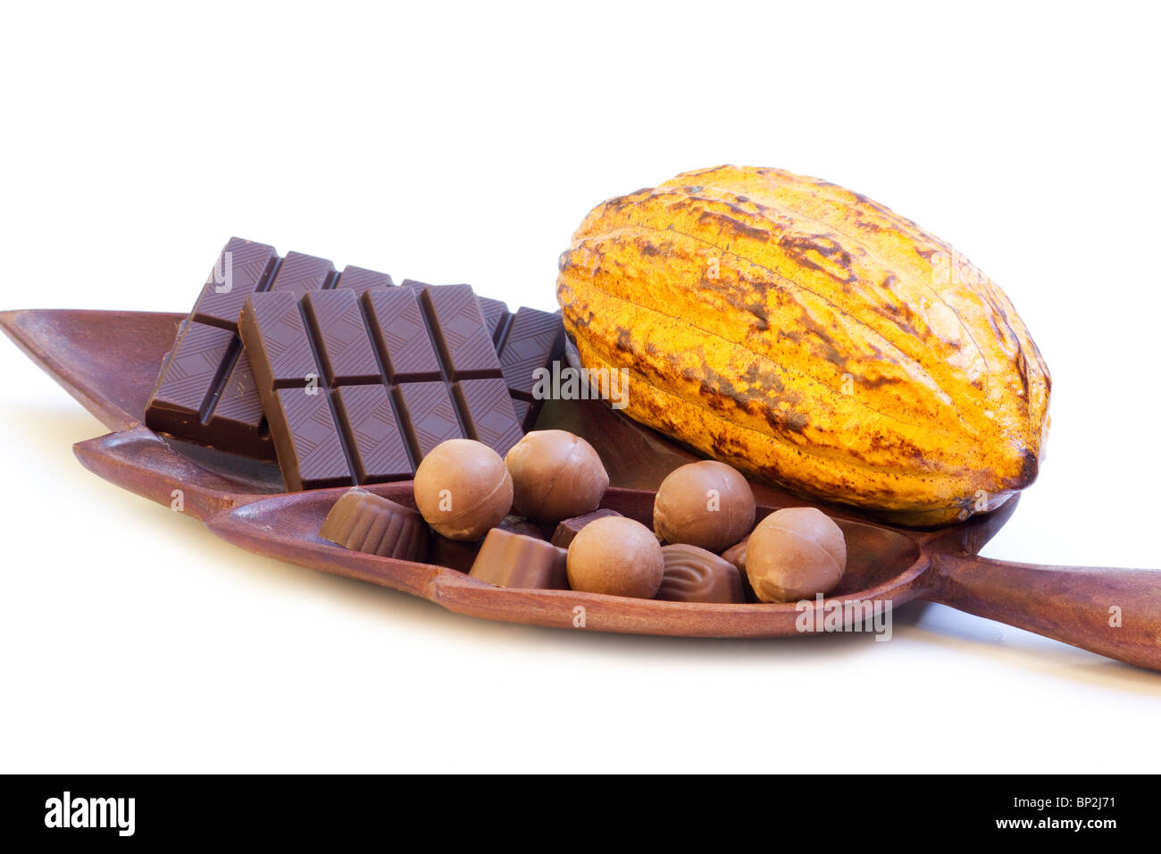 Close-up di cacao pod di frutta con il cioccolato su una foglia a forma di vassoio di legno su sfondo bianco Foto Stock