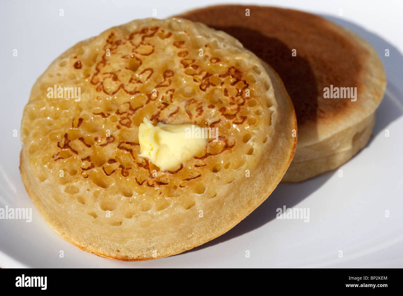 Noce di burro fusione su un tradizionale crumpet britannico Foto Stock Noce di burro fusione su un tradizionale crumpet britannico Foto Stock