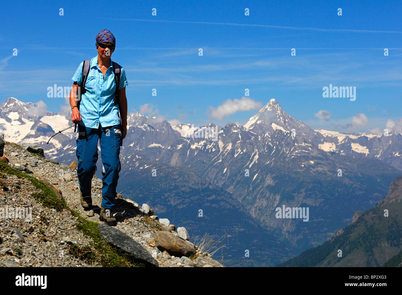 Escursionista femmina escursionismo su uno stretto sentiero di montagna alta sopra la Valle del Rodano in Alpi Pennine, Vallese, Svizzera Foto Stock