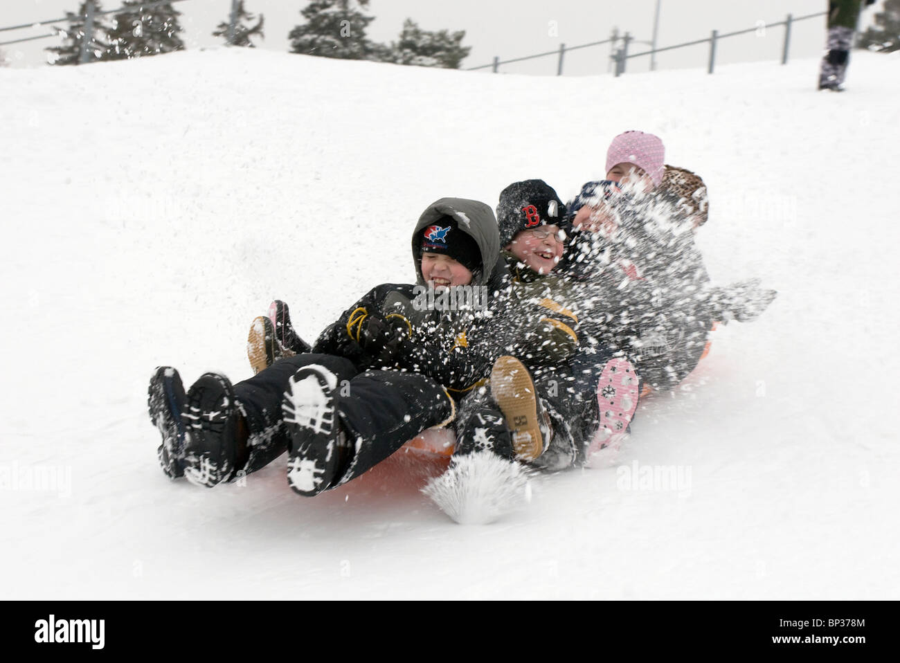 I bambini in sella a una slitta una discesa in neve a Omaha's Memorial Park Foto Stock