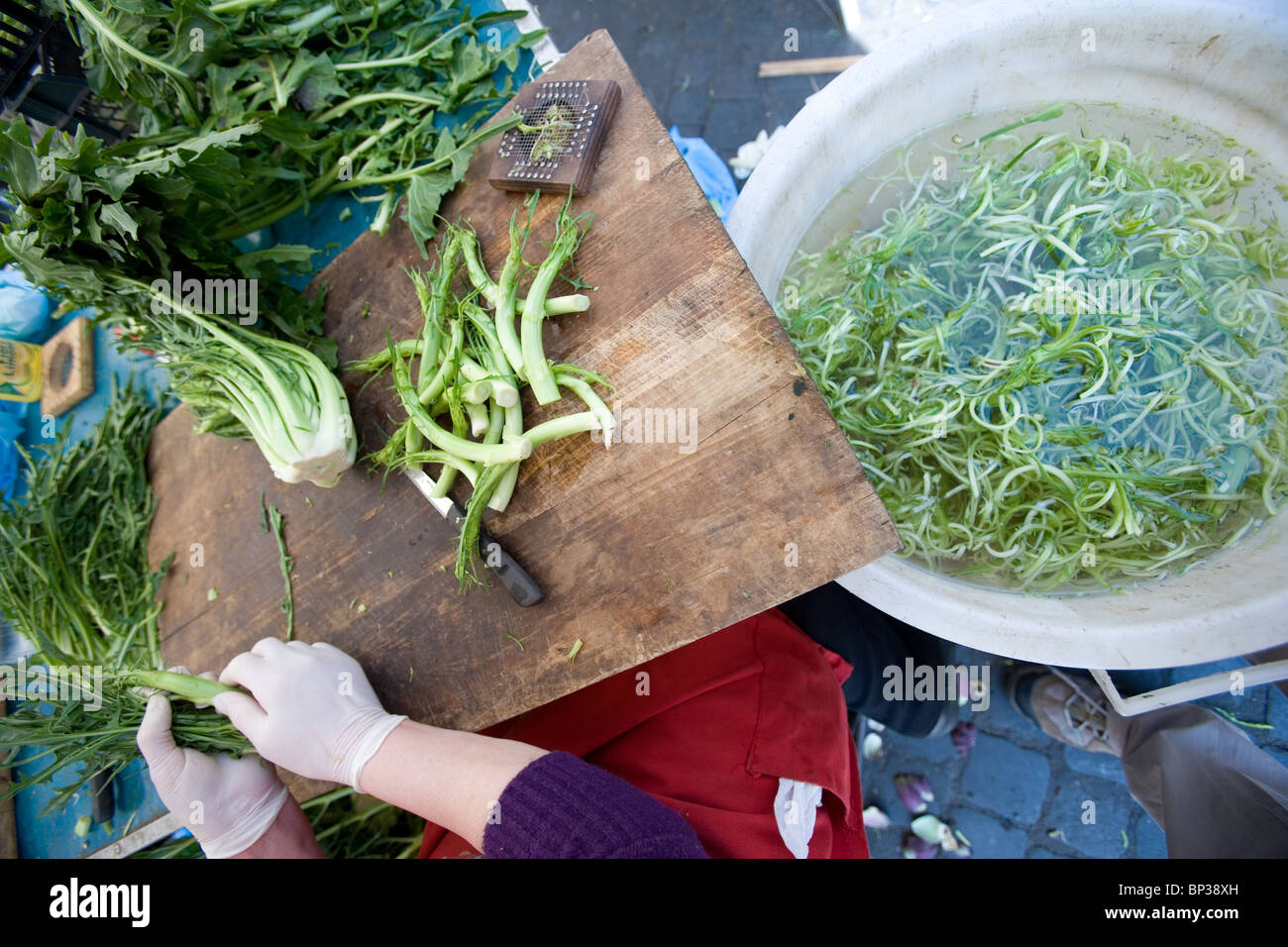 Le mani con guanti in lattice tagliato crudo fresco cicoria tipici nel mercato di via Roma Italia Foto Stock