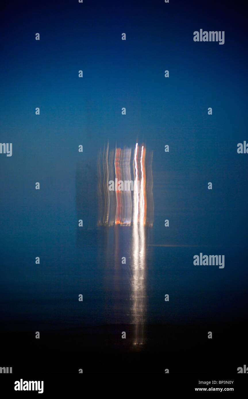 Una lunga esposizione di off shore oil rig di notte mostra percorsi causata dal movimento del mare Foto Stock