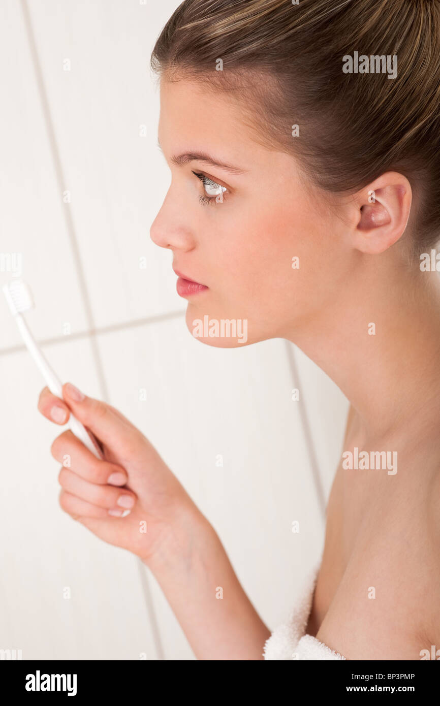 Donna bionda con spazzolino da denti bianchi in bagno Foto Stock