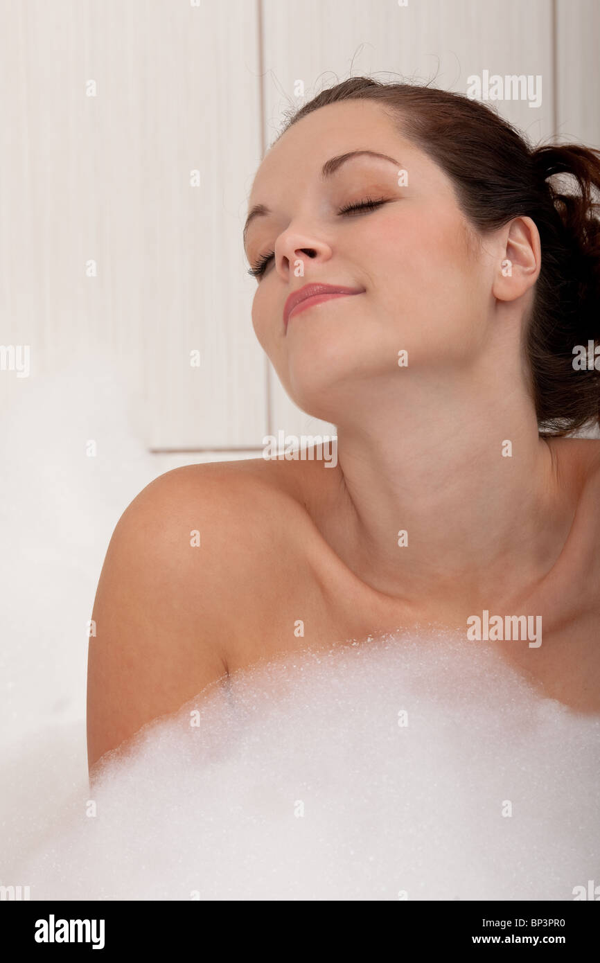 Bella giovane donna nella vasca da bagno con schiuma Foto Stock