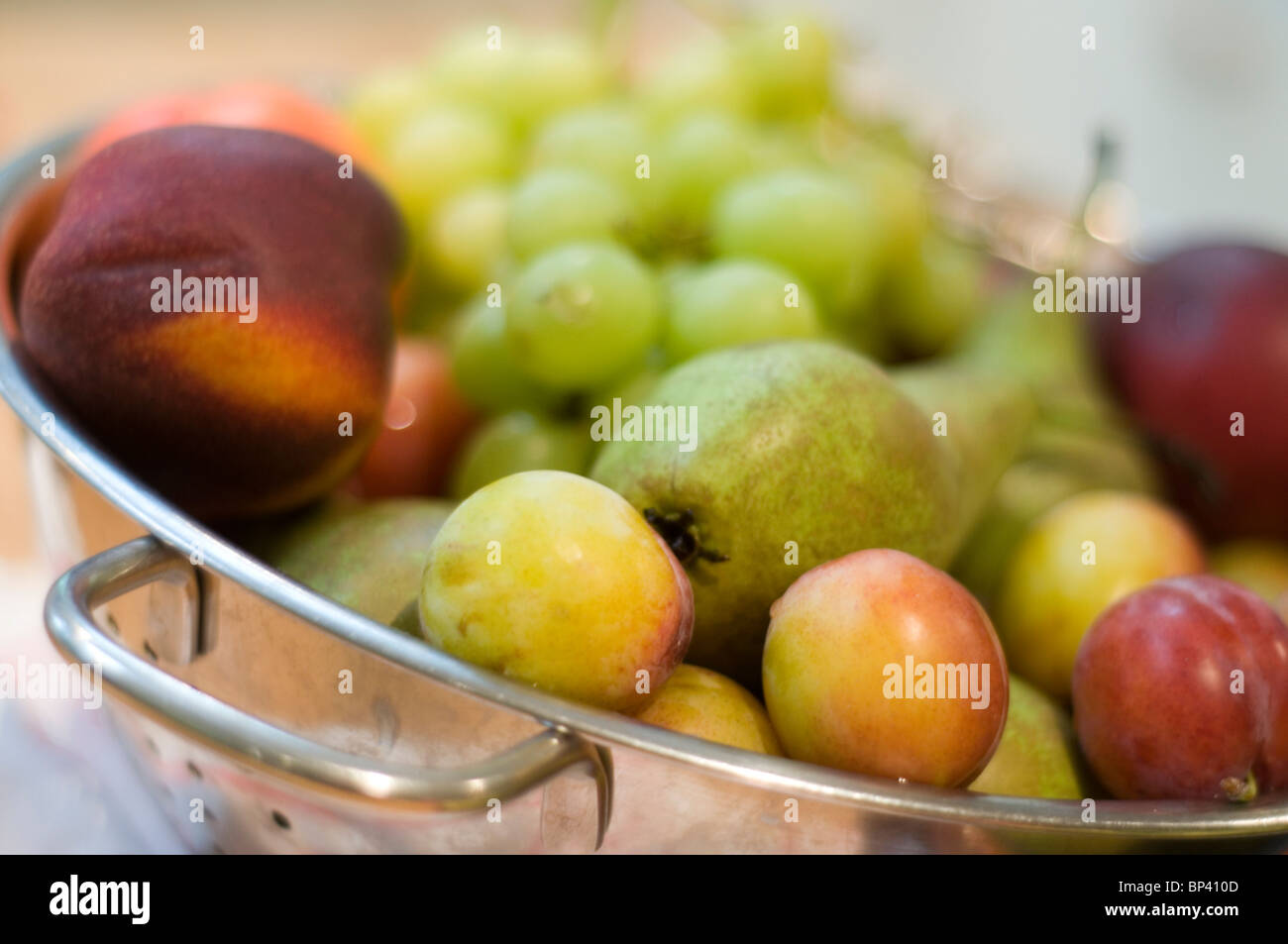 Uno scolapasta della frutta comprese le prugne, l'uva, le mele e le pesche noci Foto Stock