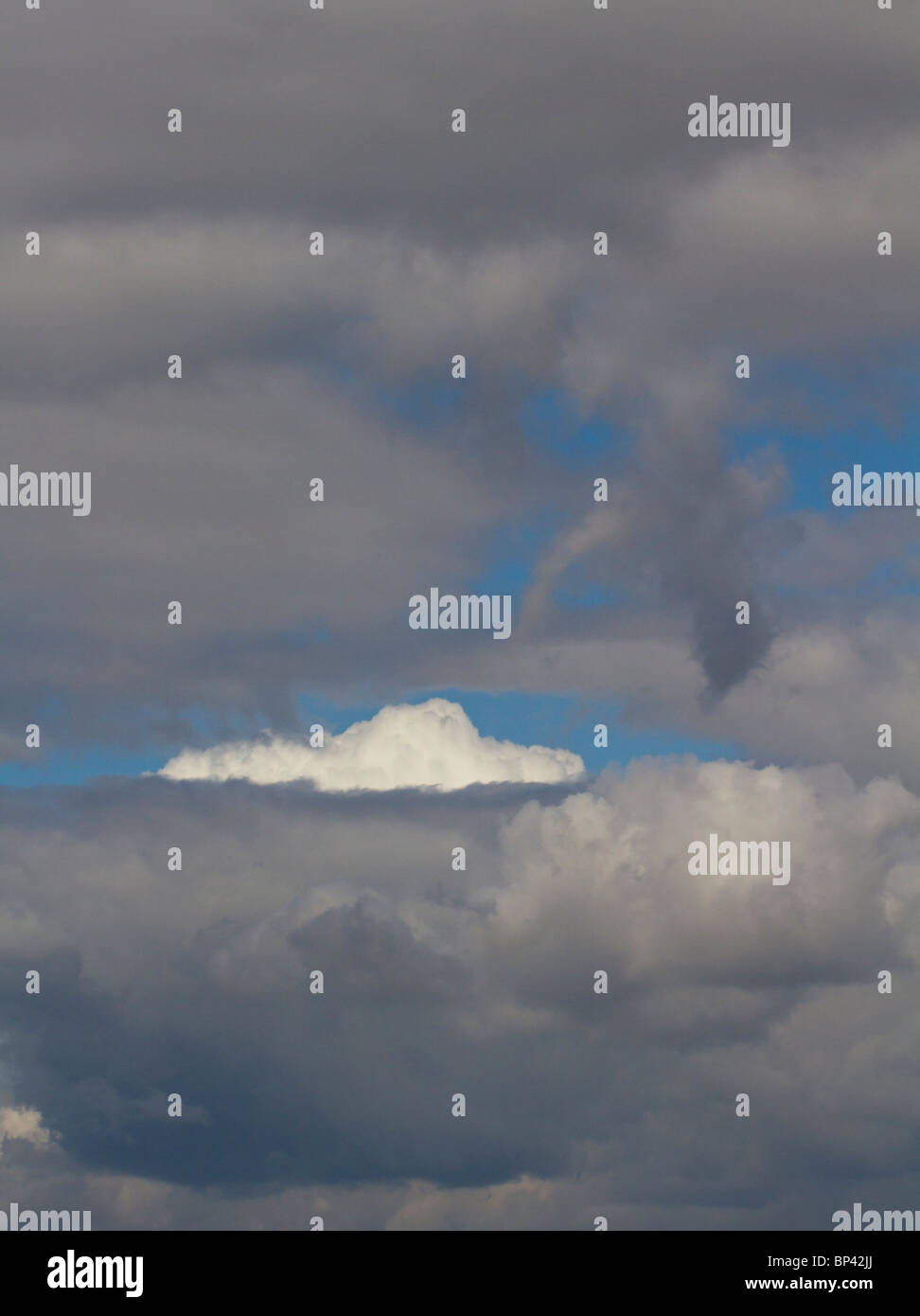 Una luminosa nuvola bianca tra Dark nuvole di tempesta Foto Stock