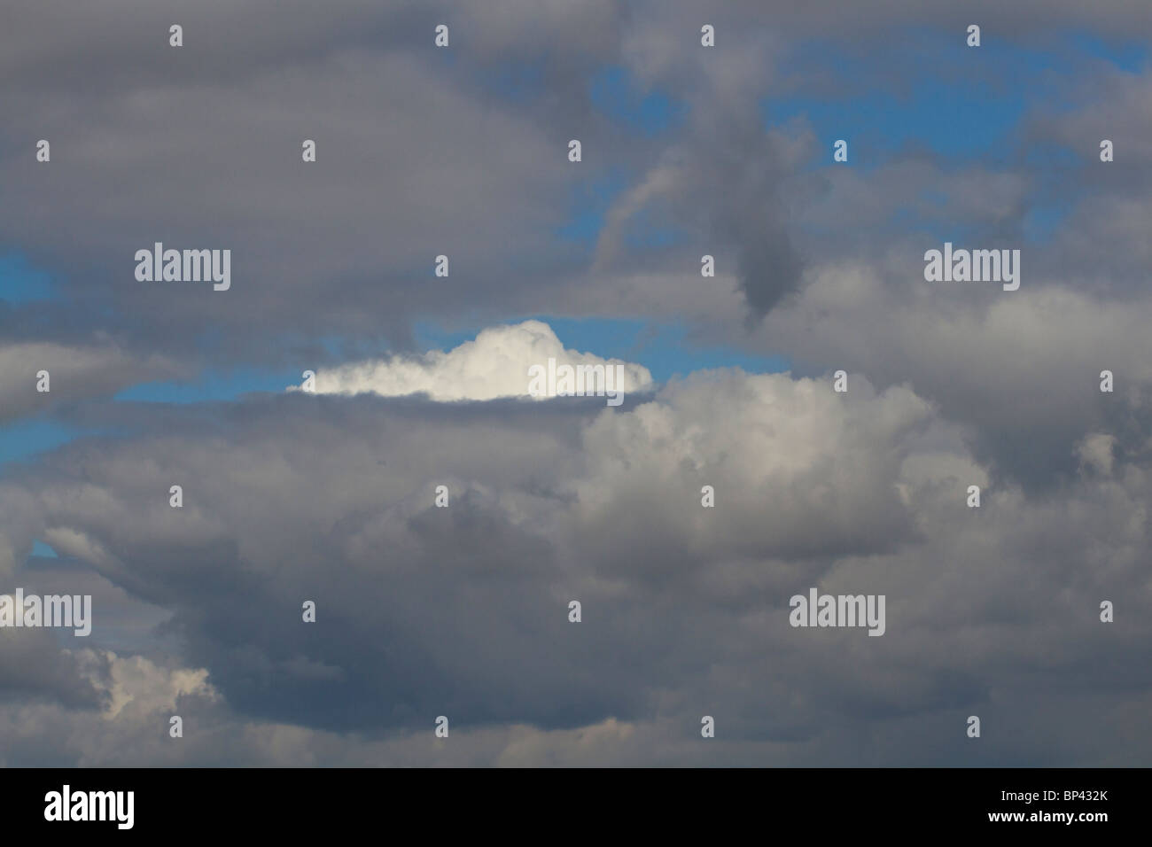 Una luminosa nuvola bianca tra Dark nuvole di tempesta Foto Stock