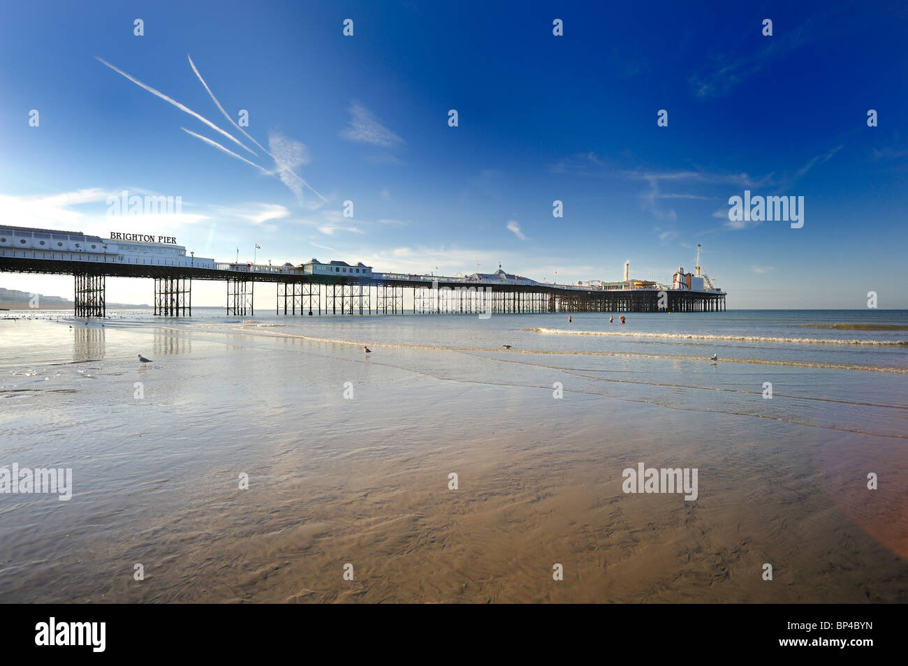 Tre persone andare a nuotare con la bassa marea dal Molo di Brighton Foto Stock