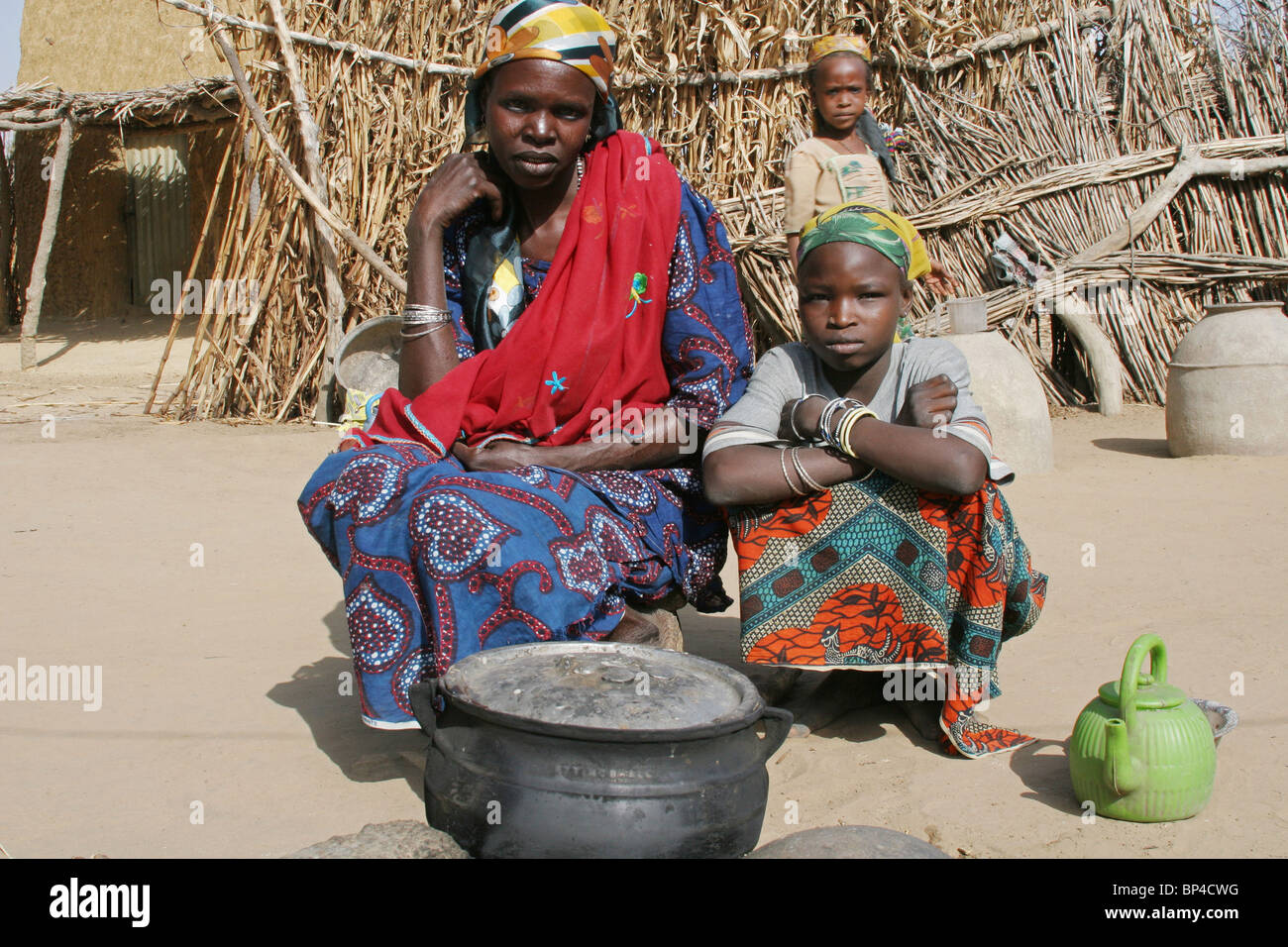 Una donna africana per la cottura con le sue figlie in un tradizionale camp nella Nigeria del nord Africa occidentale Foto Stock