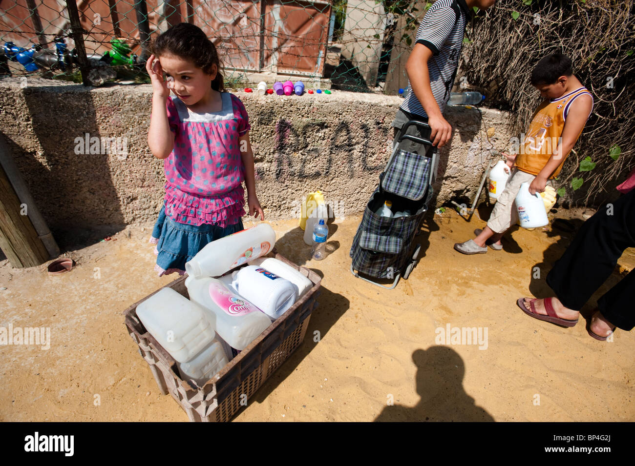 Campo profughi palestinese i bambini riempiono le bottiglie di plastica in corrispondenza di un rubinetto pubblico a causa delle restrizioni israeliane sull uso di acqua Foto Stock