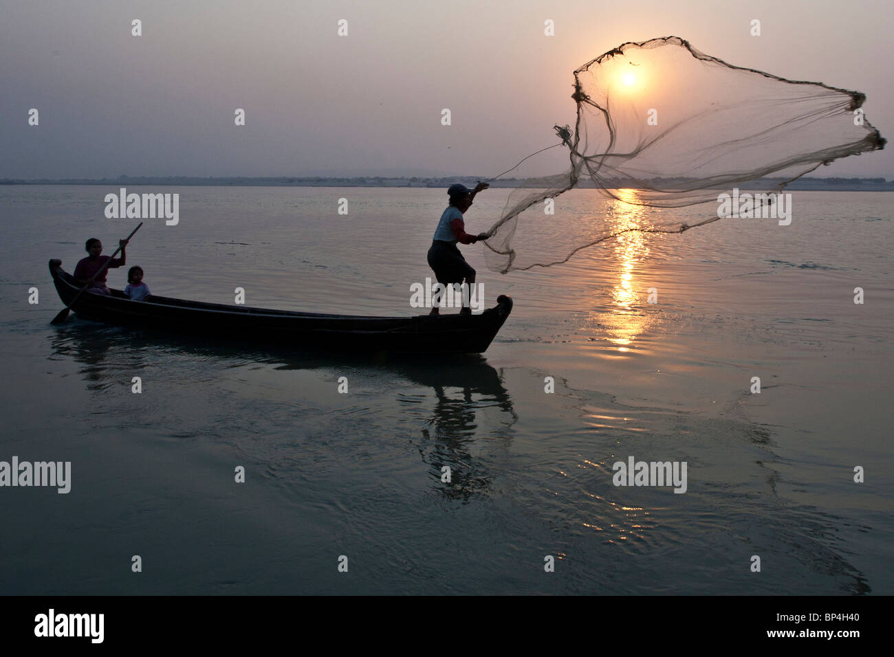 Una famiglia di pescatori lavora insieme a pescare sul fiume Irrawaddy al tramonto vicino a Mandalay, Myanmar. Foto Stock