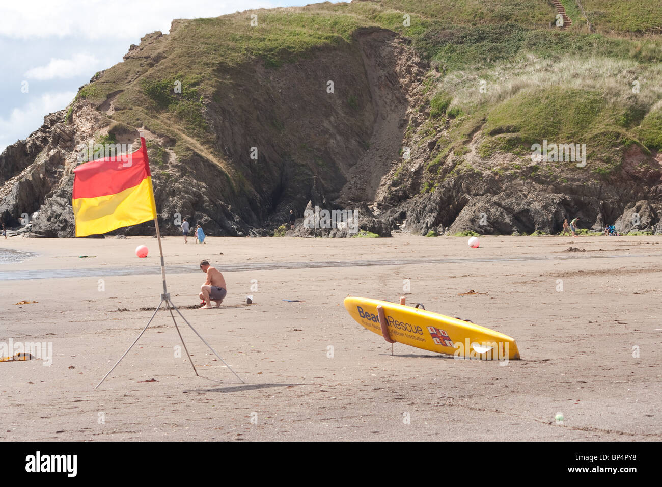 Spiaggia sicurezza utilizzando il rosso e il giallo di bandiera sistema NEL REGNO UNITO. Salvataggio con la tavola da surf è presente come bene. Foto Stock