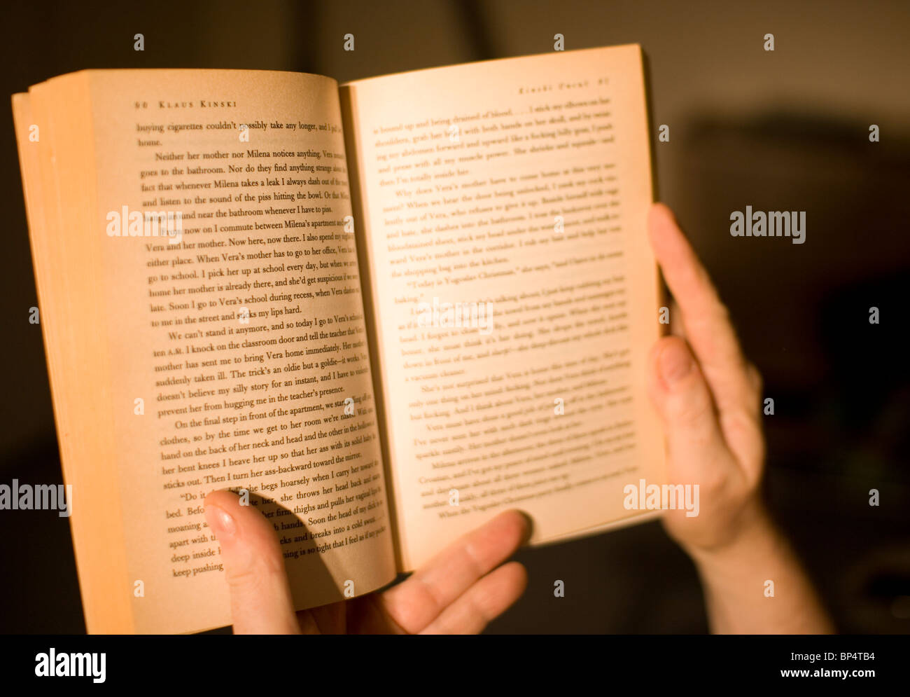 La lettura di un libro in brossura dalla luce artificiale. Foto Stock