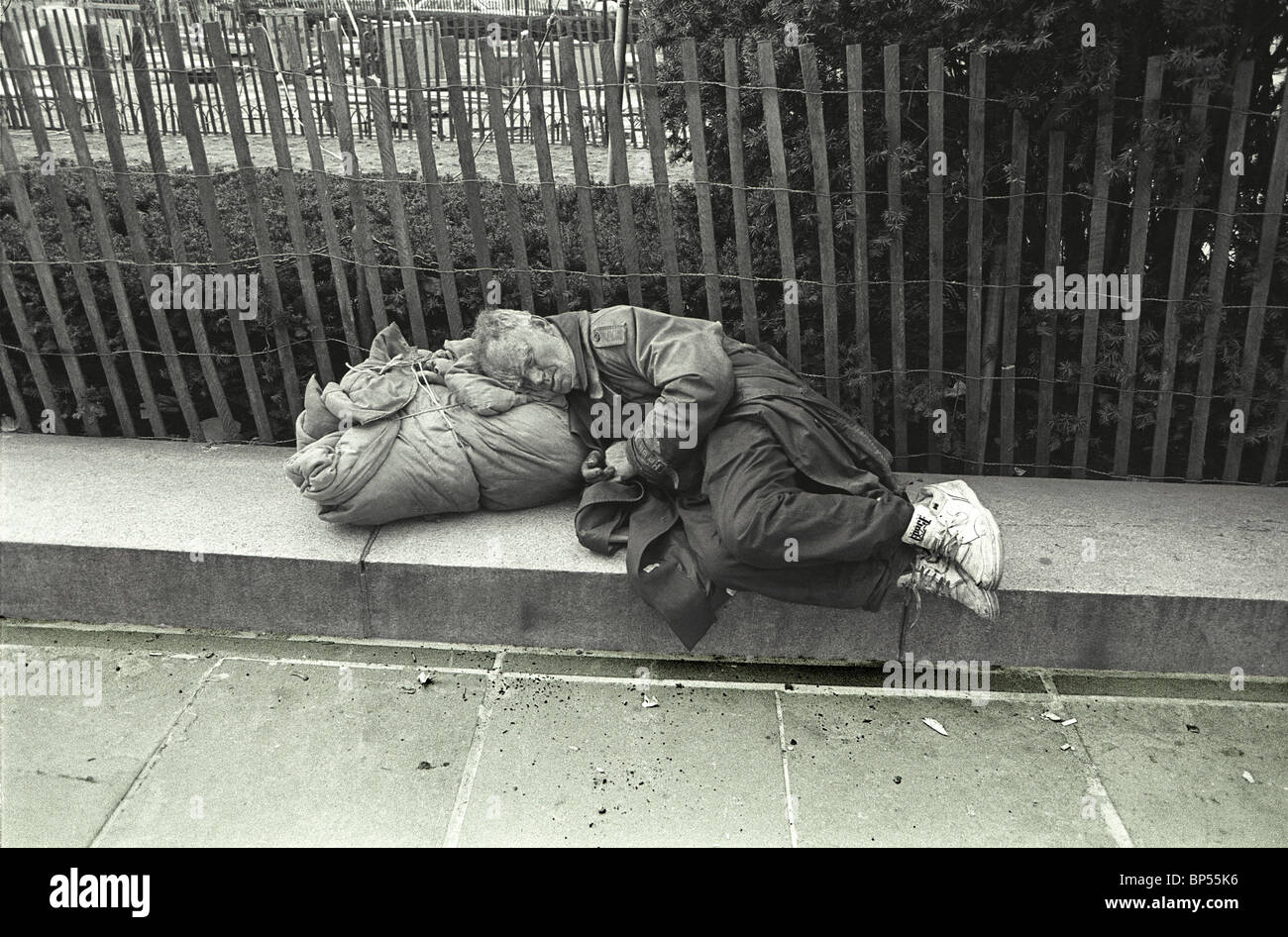Senzatetto vecchio uomo dorme lungo la Quinta Avenue appena al di fuori del Central Park di New York City. Foto Stock