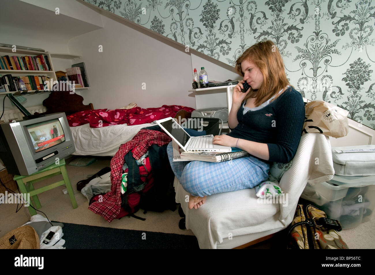 Ragazza adolescente multi-tasking su telefono portatile e guardare la televisione Foto Stock