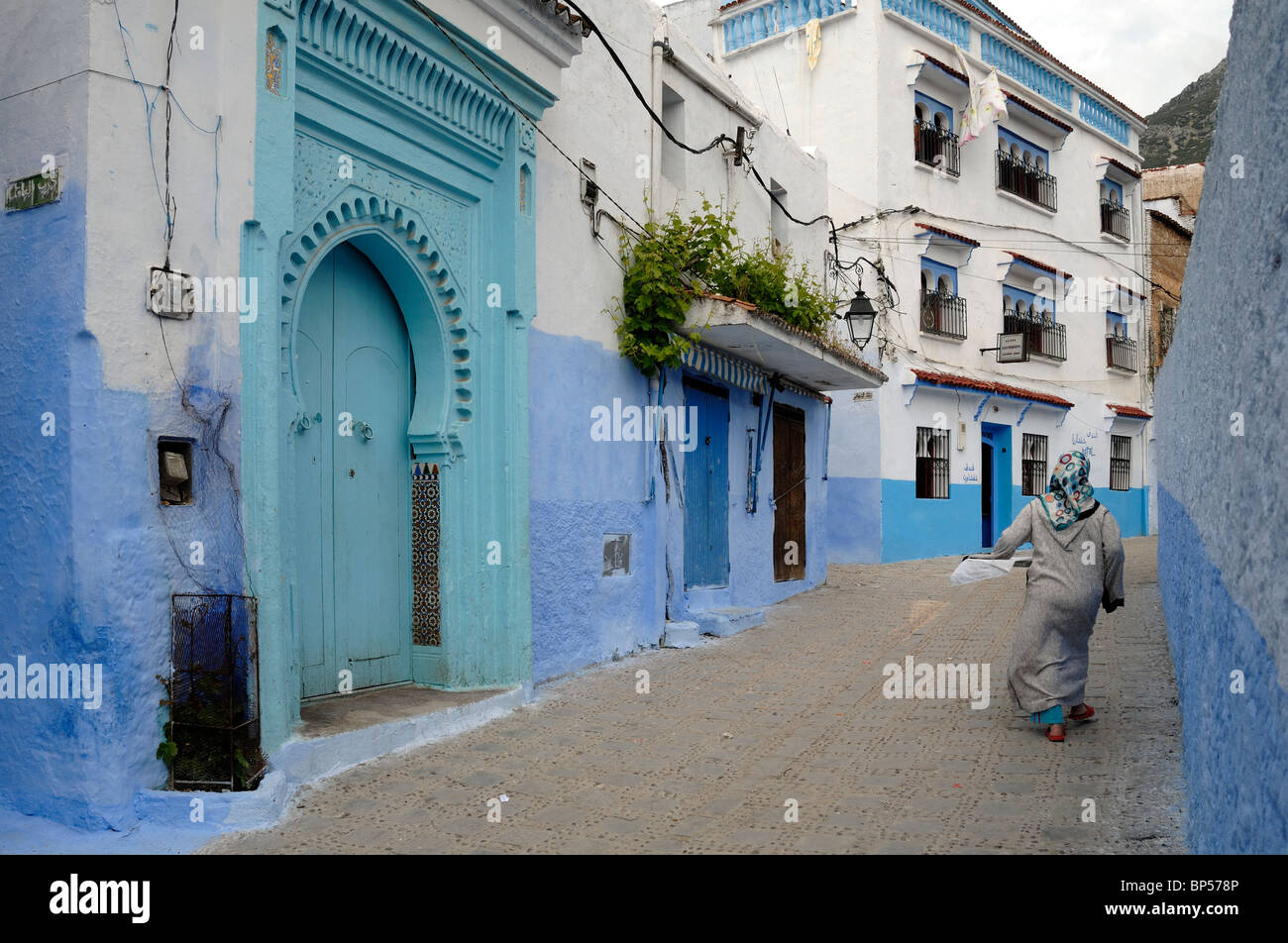 Scena di strada, donna marocchina, Case blu & blu o porta di ingresso, Chefchaouen, Marocco Foto Stock