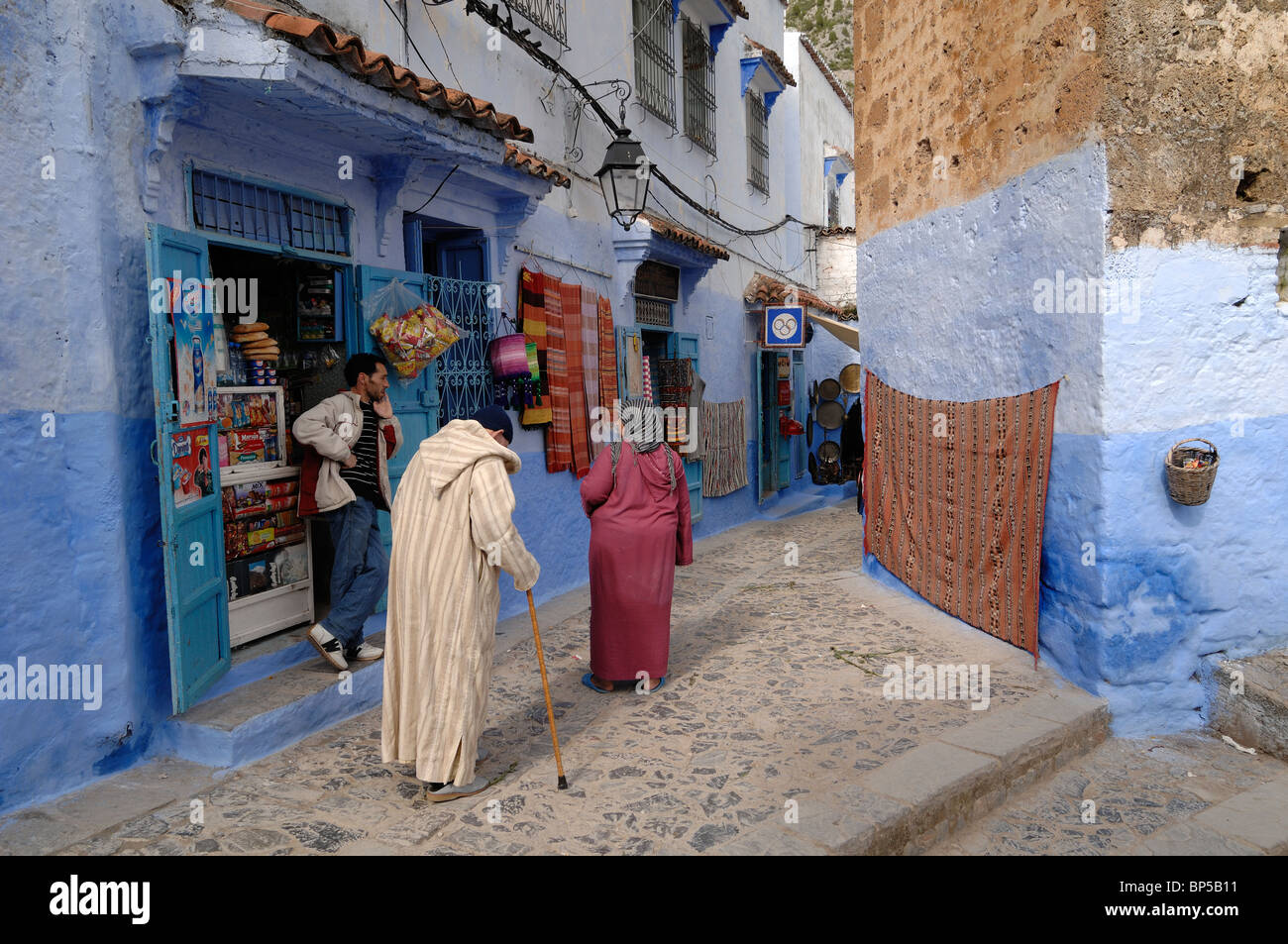 Negozi tradizionali, Corner Store, minimarket o Corner Shop e Old Marocchino coppia in strade di Chefchaouen, Marocco Foto Stock