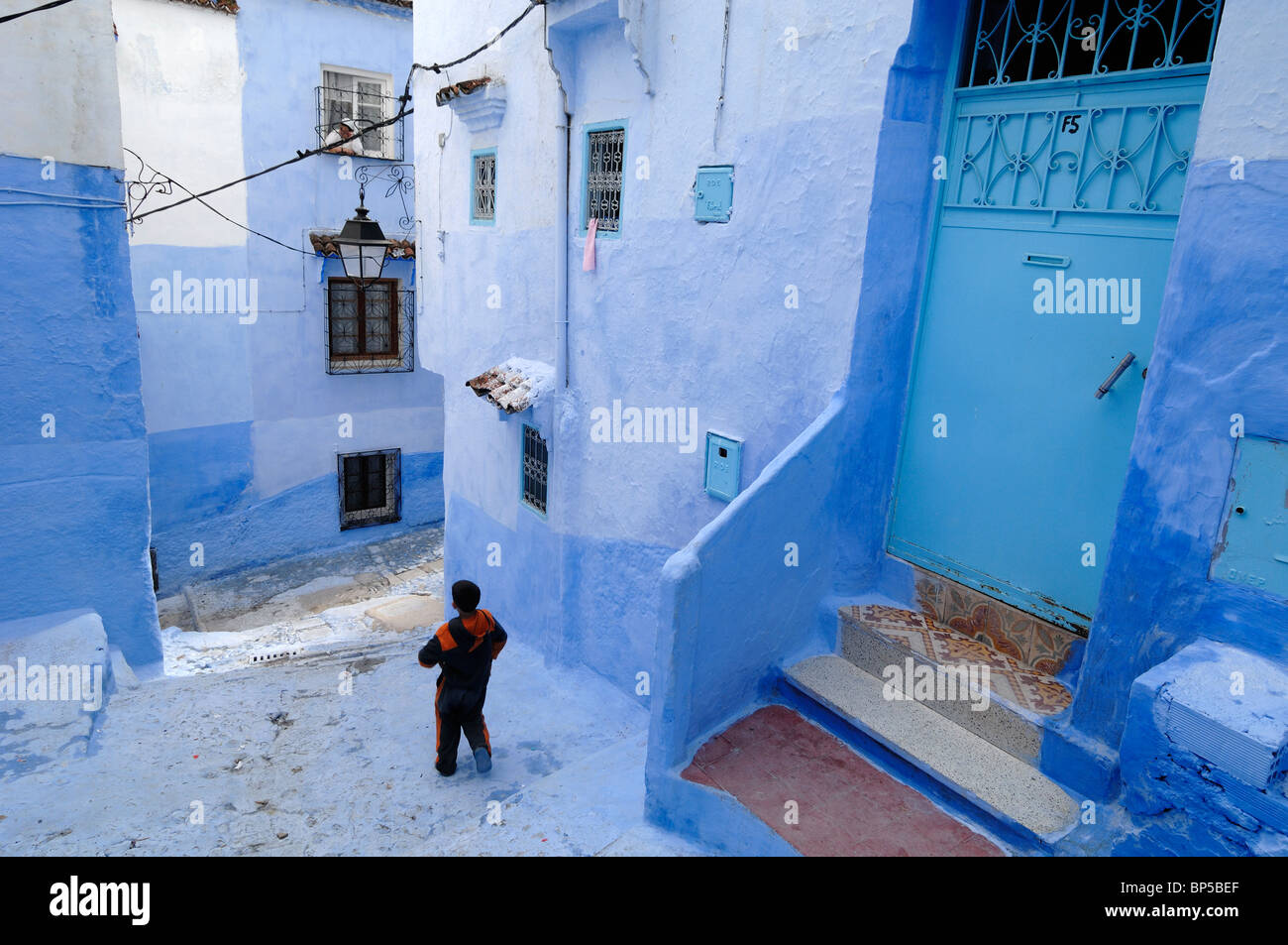 Ragazzo marocchino che corre attraverso le strade blu di Chefchaouen, Marocco Foto Stock