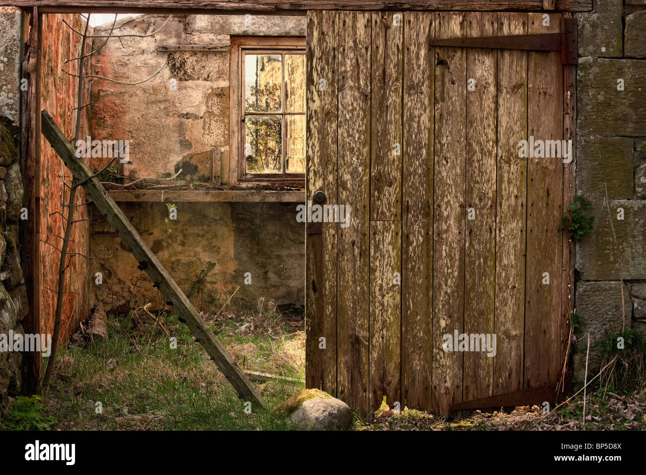 Northumberland, Inghilterra; un edificio abbandonato in rovine con la rottura di una porta di legno Foto Stock