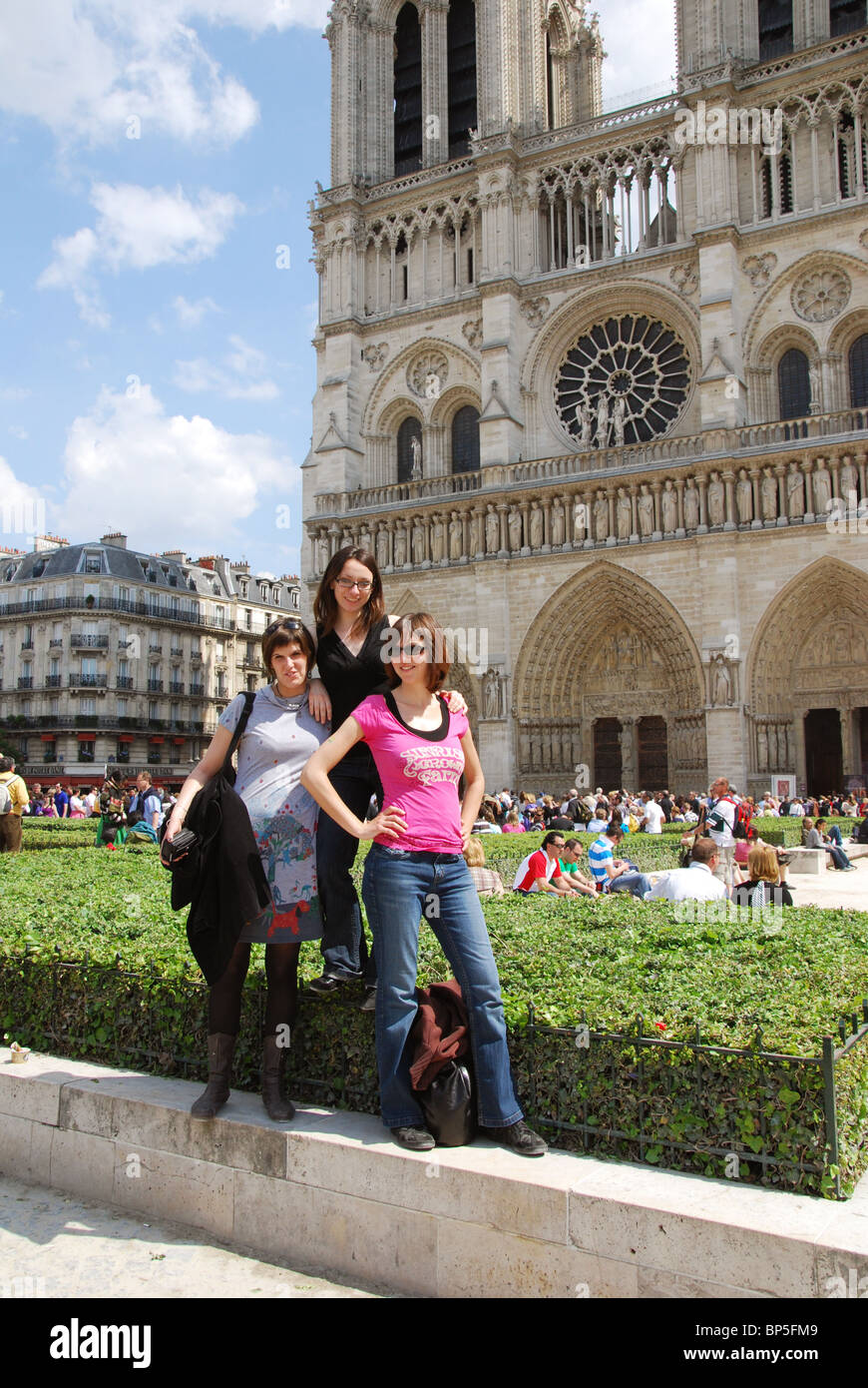3 giovani donne in posa davanti alla Cattedrale di Notre Dame Parigi Francia Foto Stock