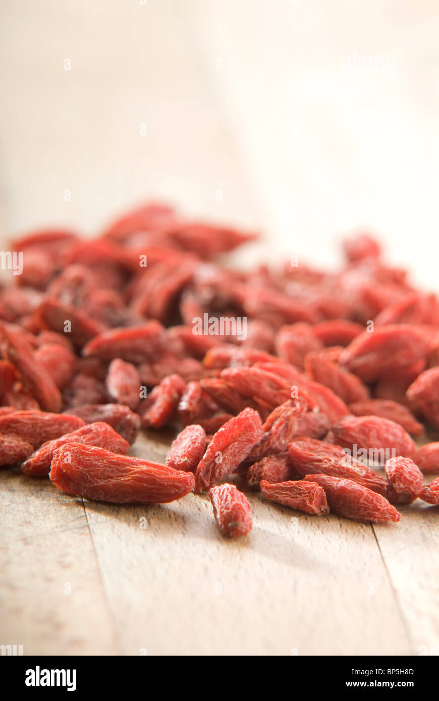 Pila di red goji bacche (Lycium chinense) su pannello di legno Foto Stock