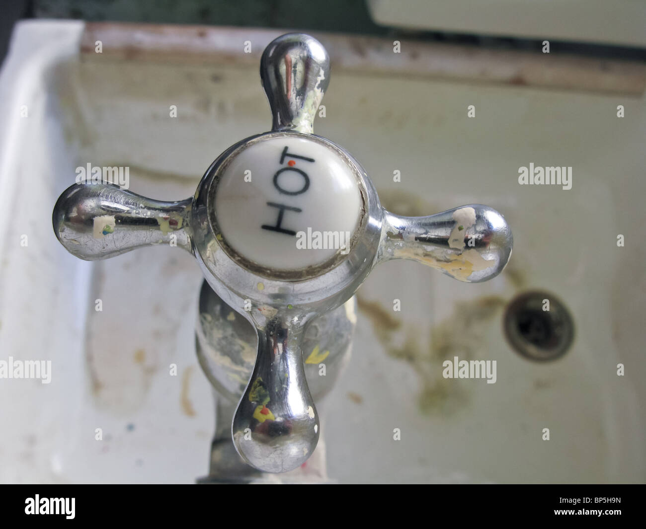 Chrome rubinetto acqua calda visualizzati tramite un profondo maggiordomi lavandino con acqua dura di depositi di calcare sulla base di sporco area di drain Foto Stock