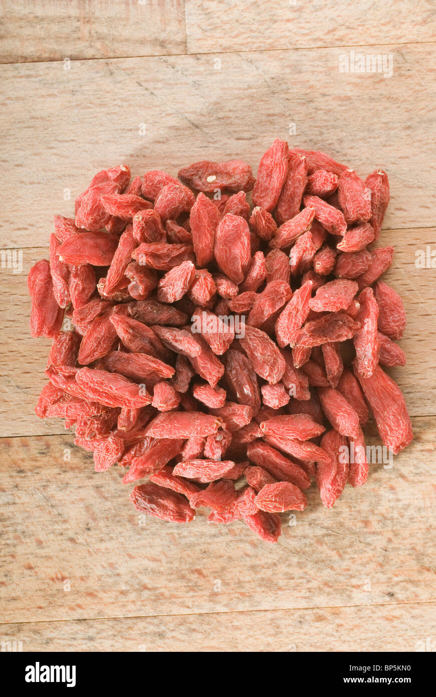 Pila di red goji bacche (Lycium chinense) su pannello di legno Foto Stock