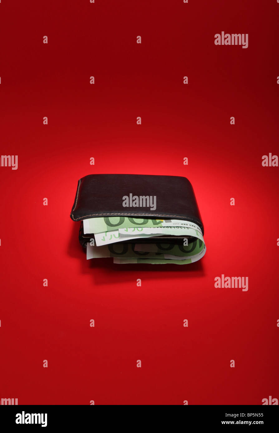 Un nero portafoglio in pelle con denaro su un brillante sfondo rosso, moneta è 300 Euro Foto Stock