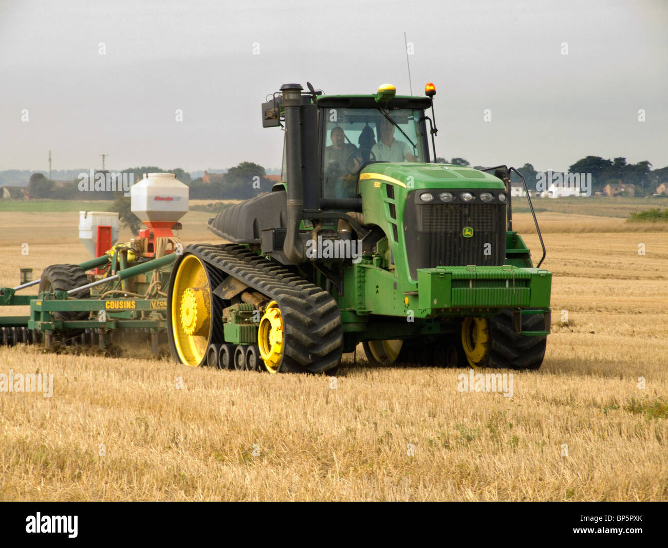 John Deere trattore con cingoli in gomma rompendo il suolo pronto per l'aratura dopo il raccolto di mais in un campo di Norfolk Foto Stock