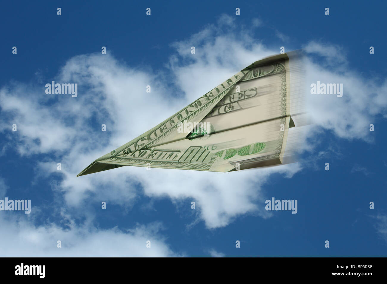 Un aeroplano di carta fatta da un centinaio di US dollar banconota battenti con moto contro uno sfondo di cielo blu e nuvole bianche Foto Stock