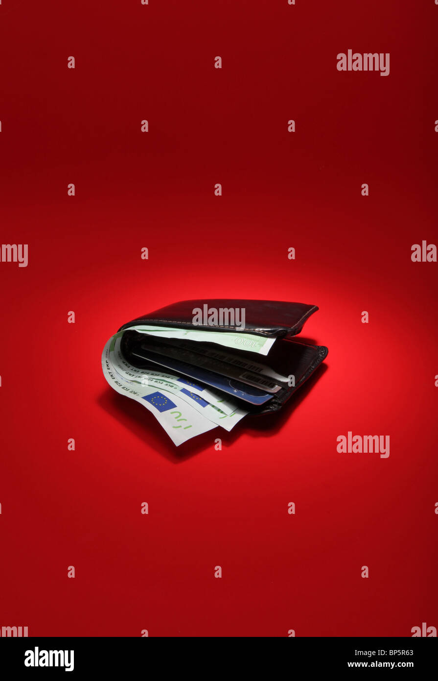 Un nero portafoglio in pelle con denaro su un brillante sfondo rosso, moneta è 300 Euro Foto Stock