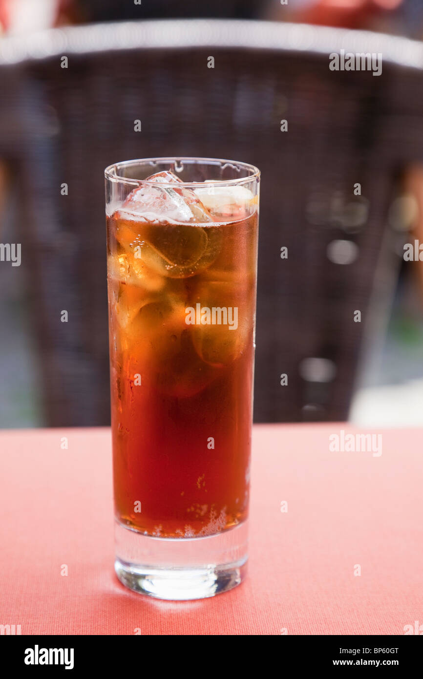 L'Europa. Bicchiere pieno di tè freddo con cubetti di ghiaccio e una fetta di limone su un tavolo in un caffè Foto Stock