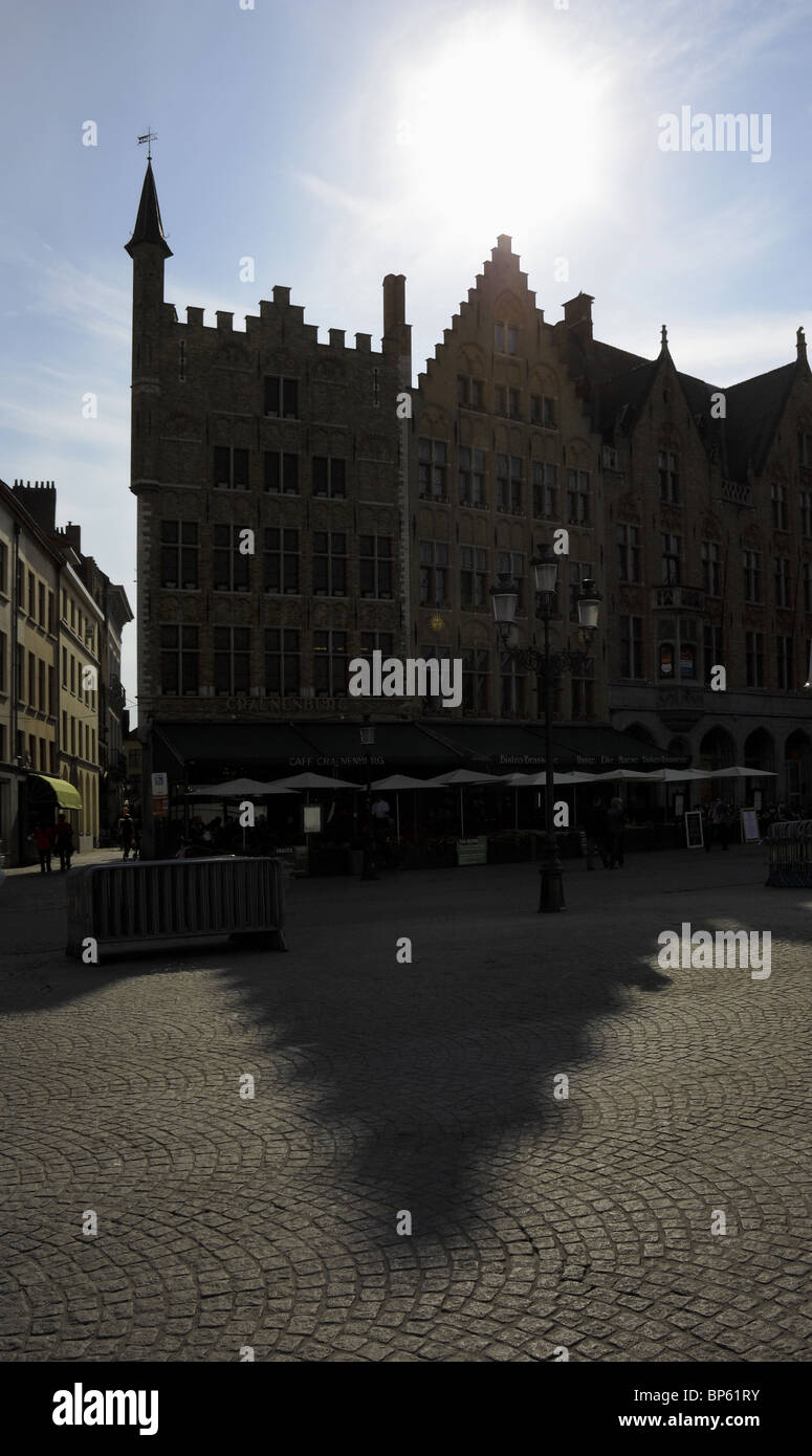 Silhouette di tetti a capanna e lunga ombra nella piazza del mercato di Bruges, Belgio Foto Stock