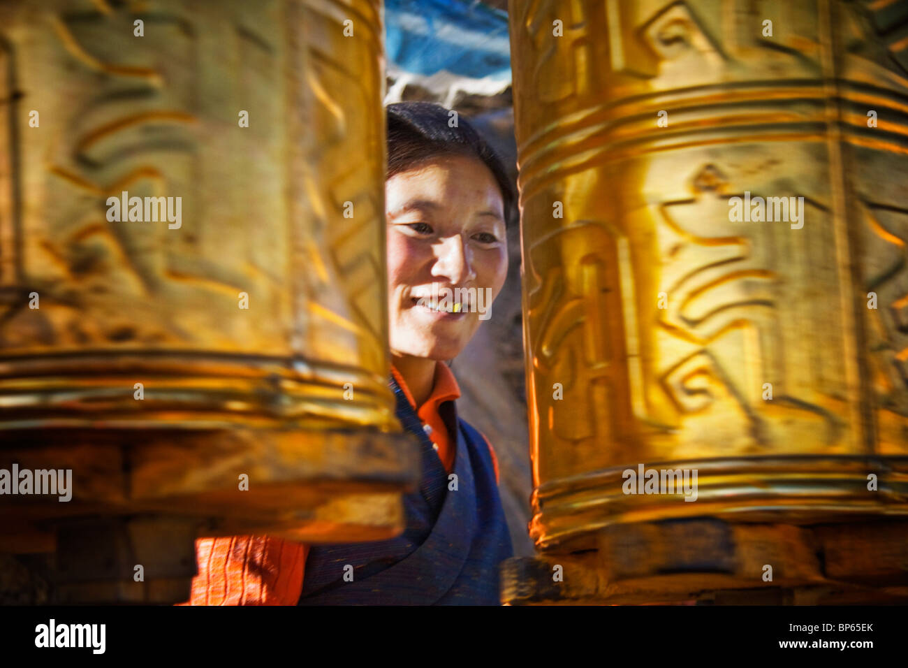 Una femmina di pellegrino gira golden mani ruote della preghiera sul Tashilhunpo kora a Shigatse, nel Tibet Foto Stock