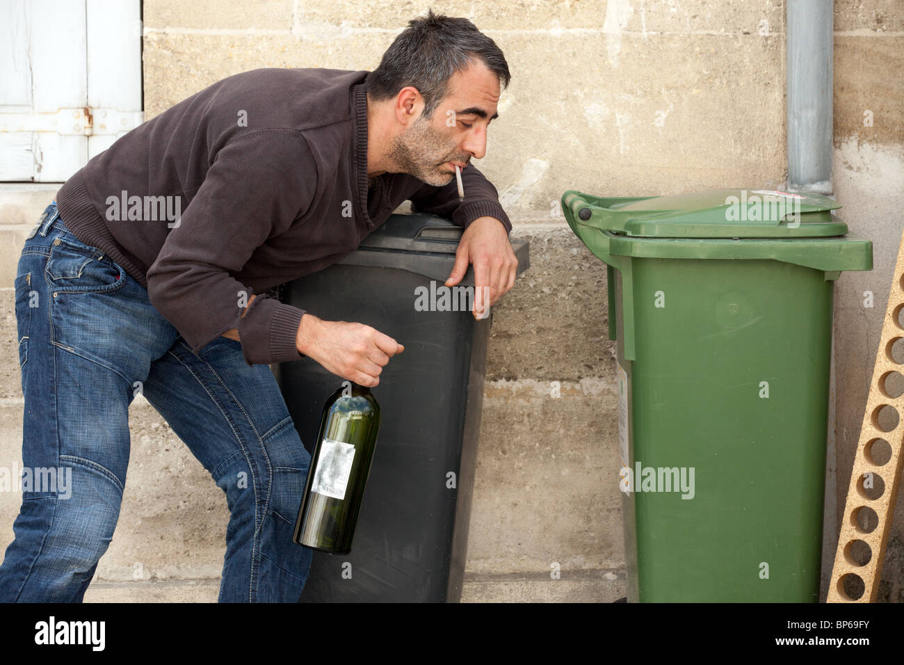 Povero uomo ubriaco in piedi vicino al cestino in strada di città Foto Stock