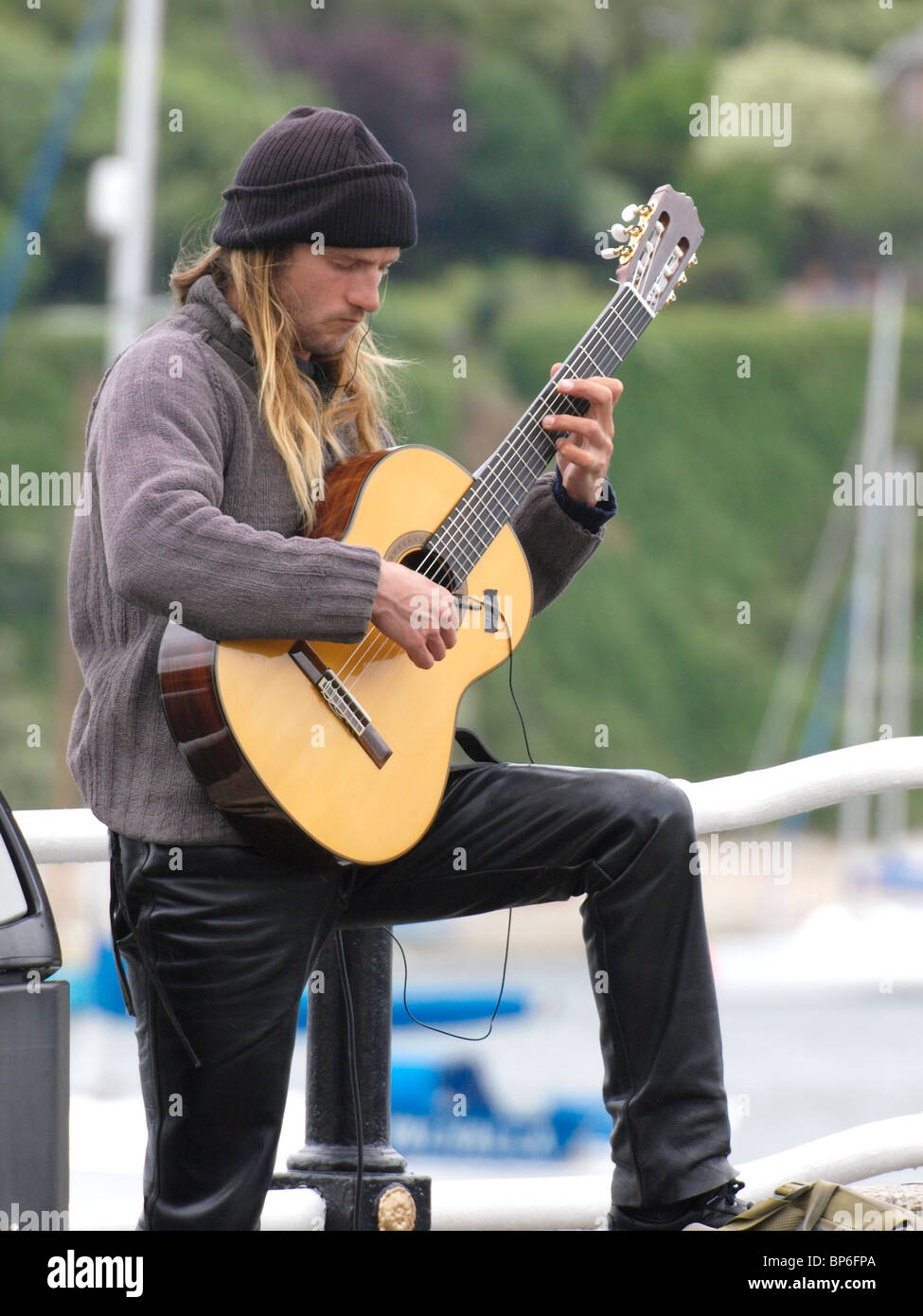 Busker suonare una chitarra spagnola, Fowey, Cornwall, Regno Unito Foto Stock