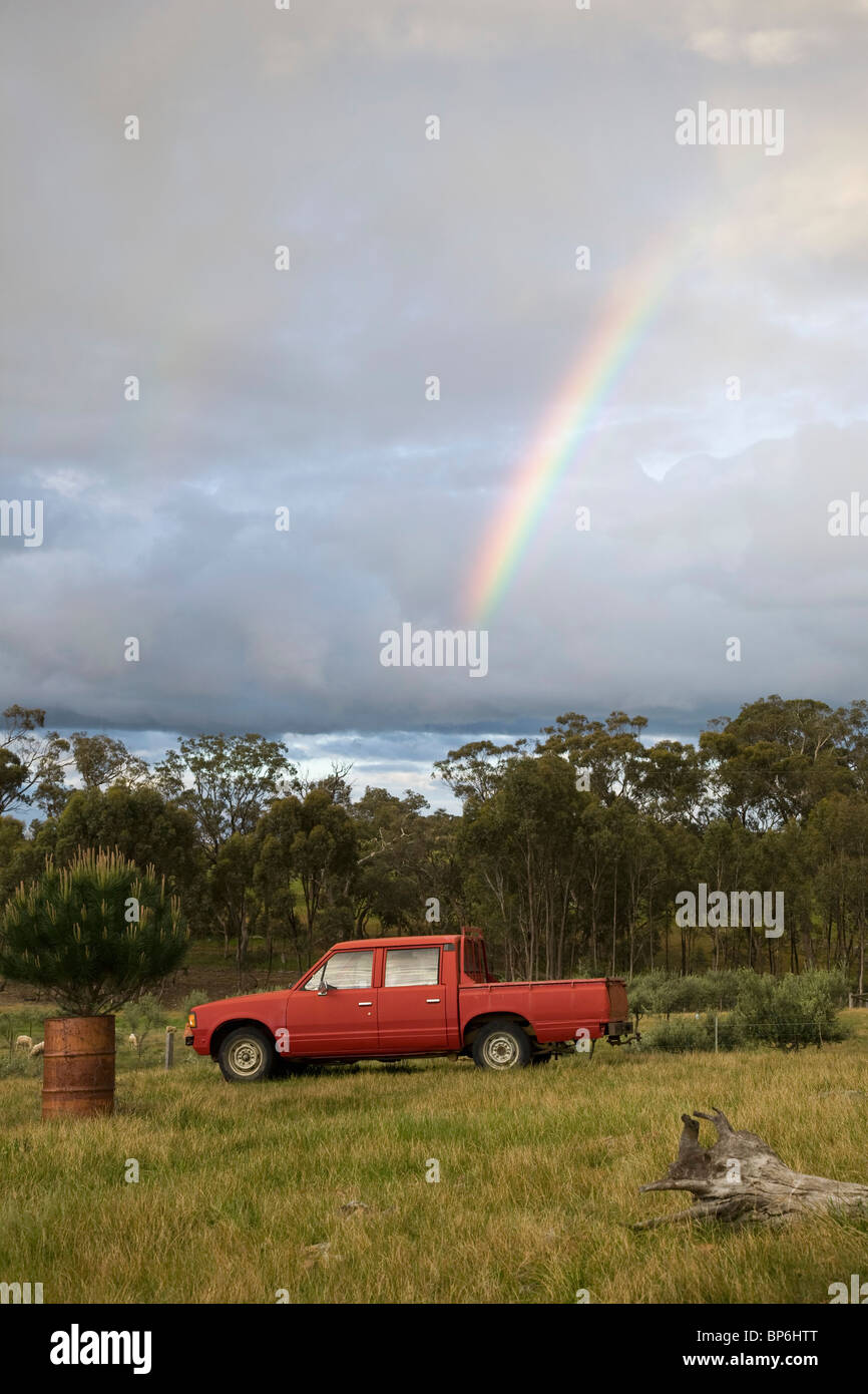 Un arcobaleno nel cielo sopra un pick-up truck in un campo Foto Stock