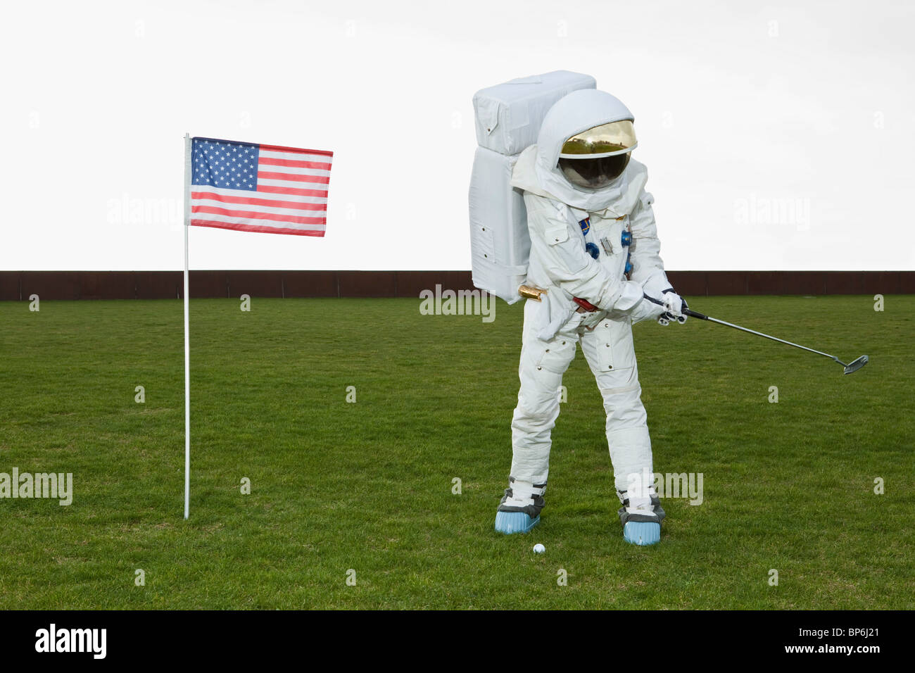 Un astronauta oscillazione un golf club accanto a una bandiera americana Foto Stock