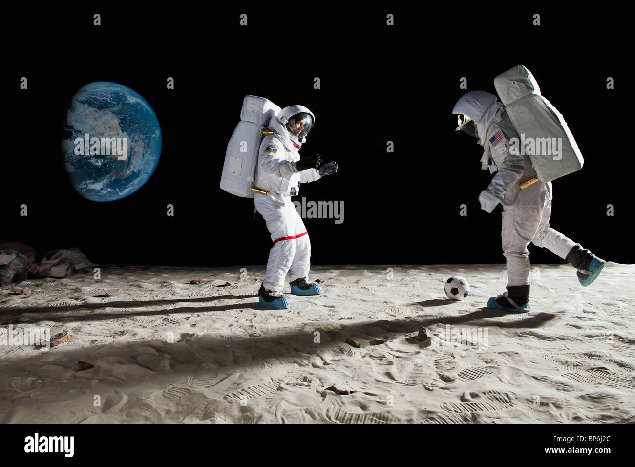 Due astronauti che giocano a calcio sulla luna Foto Stock