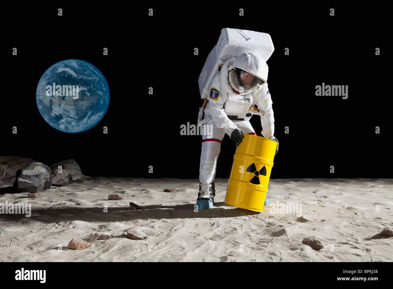 Un astronauta laminazione di un tamburo di materiale tossico sulla superficie lunare Foto Stock