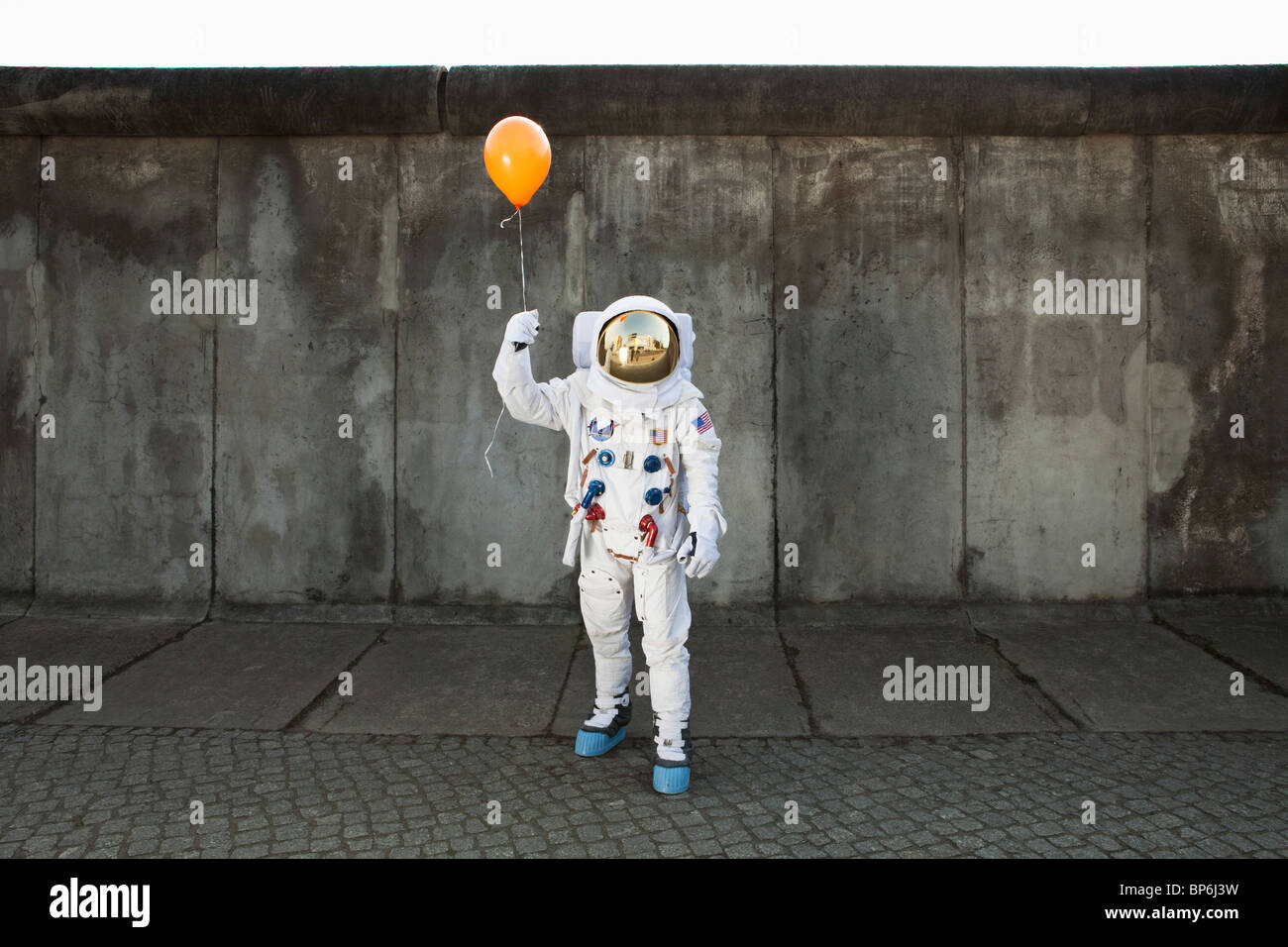 Un astronauta su un marciapiede in città tenendo un palloncino Foto Stock