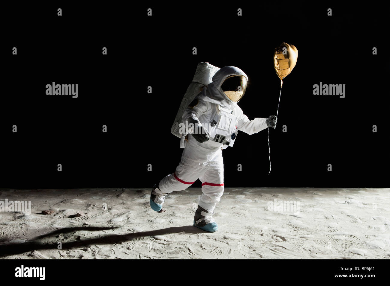 Un astronauta sulla luna tenendo un cuore a forma di palloncino elio Foto Stock