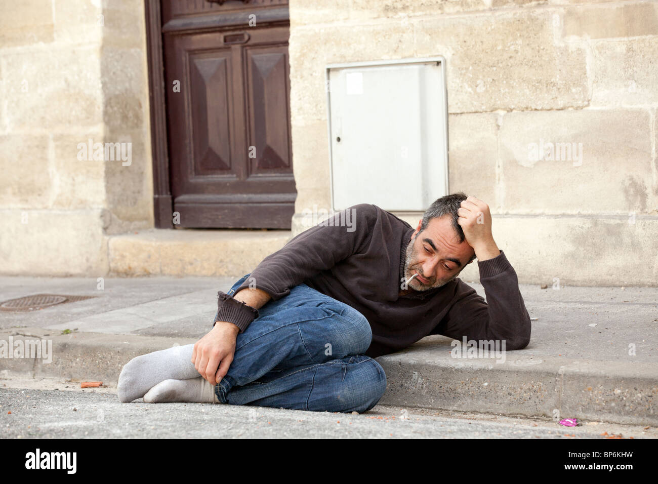 Poveri senzatetto uomo disteso vicino alla porta di casa in una strada di città Foto Stock